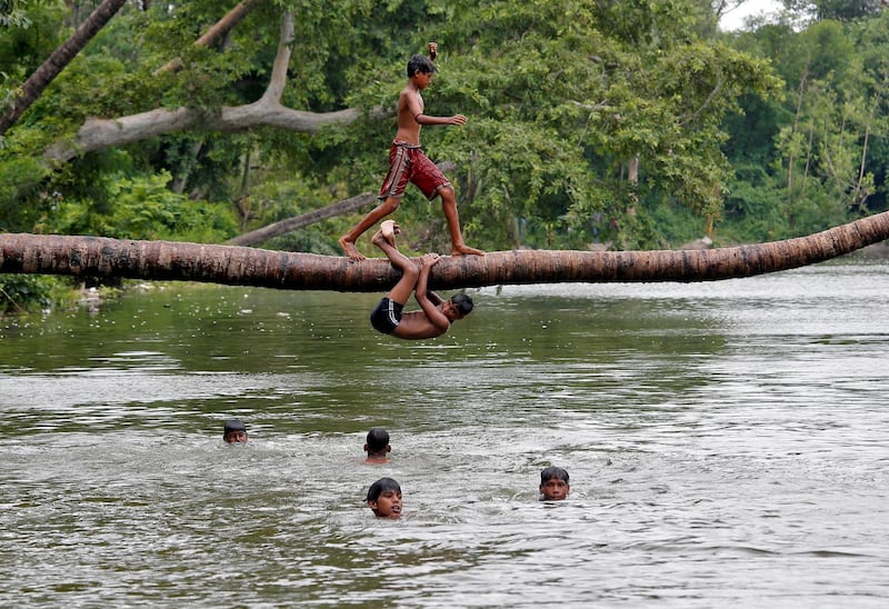 A boy prepares to jump from a fallen coconut tree into a lake on a hot summer day, amid the outbreak of the coronavirus disease in Kolkata, India. Reuters
