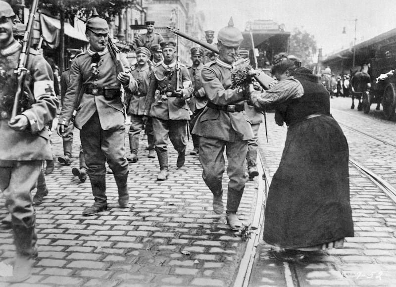 Prussian soldiers leaving Berlin for the front are given flowers by a woman.