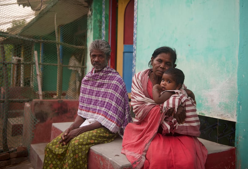 Jaya Rajamma sitting outside her house with a relative and her granddaughter. She says that she loved the sea as a child but is now scared of it and avoids looking at it at night.