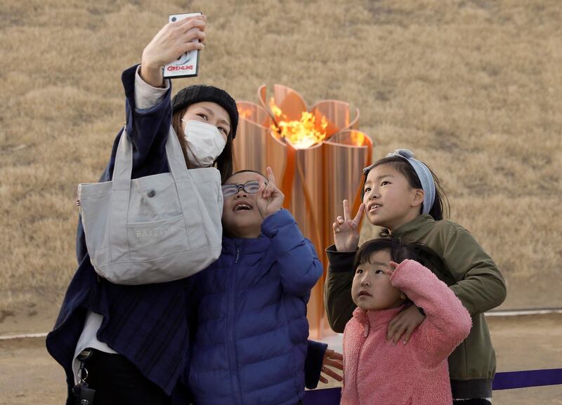 A family takes a selfie with the Olympic flame on a cauldron displayed at Ishinomaki Minamihama Tsunami Recovery Memorial Park on Friday.  EPA
