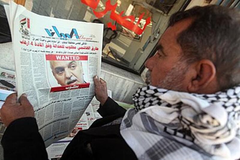 An Iraqi man looks at a newspaper featuring a front page picture of  Tariq Al Hashemi, the vice president, with the word “wanted” above his face.