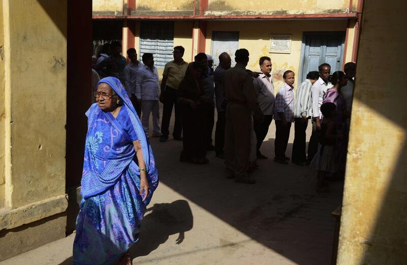 An Indian Muslim woman walks away after having marked her vote as others wait in line at a local polling station in Varanasi. Roberto Schmidt / AFP 