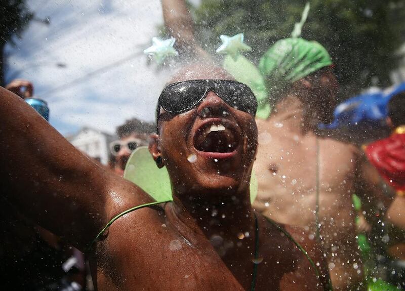 A reveller exalts while being sprayed by water from a resident during the ‘Ceu na Terra’ street carnival bloco.  Mario Tama / Getty Images