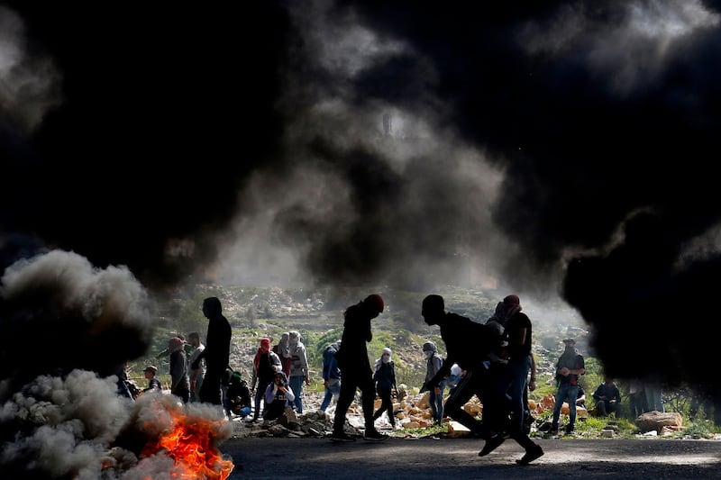 Palestinian demonstrators from Birzeit University take cover during clashes with Israeli forces in Ramallah, near the Jewish settlement of Beit El, in the occupied West Bank. AFP