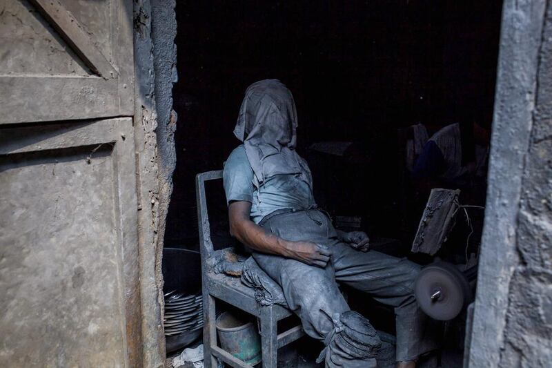 A pan polisher covers his face as he takes a rest at the Putra Logam factory in Yogyakarta, Indonesia. Ulet Ifansasti / Getty Images