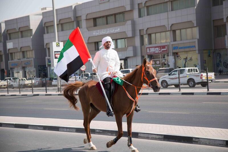 A man rides a horse while holding the UAE flag for Emirates Transport's Flag Day event in Dubai. Courtesy Emirates Transport