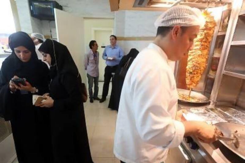 Staff from the Abu Dhabi Food Control Authority (left) inspect Beirut restaurant while the chef (right) prepares a meal at the restaurant's branch in Al Wahda Mall, Abu Dhabi. Sammy Dallal / The National