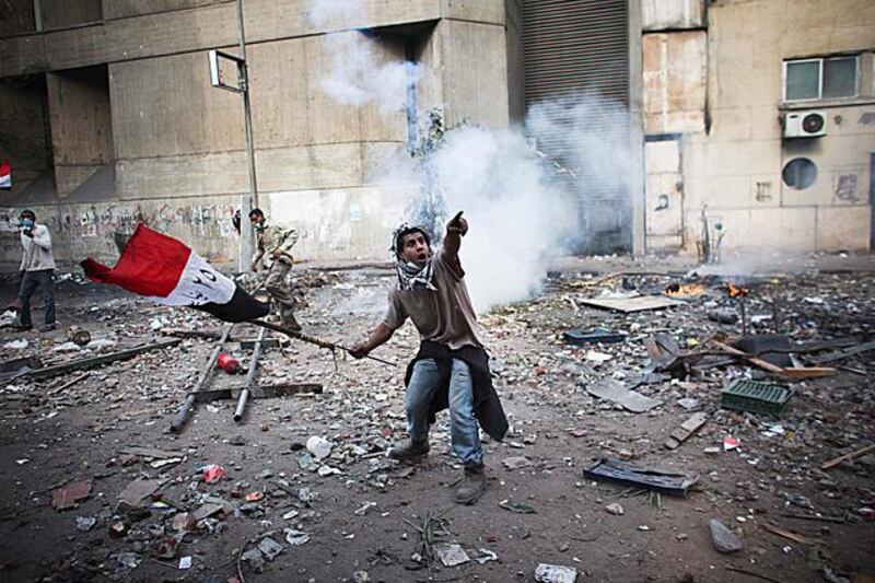 A protester points to an incoming tear gas canister during clashes with Egyptian riot police, not pictured, near Tahrir square in Cairo, Egypt, Wednesday, Nov. 23, 2011. Egyptian police are clashing with anti-government protesters for a fifth day in Cairo. Tens of thousands of protesters in Tahrir Square have rejected a promise by Egypt's military ruler to speed up a presidential election to the first half of next year. They want Field Marshal Hussein Tantawi to step down immediately in favor of an interim civilian council. (AP Photo/Tara Todras-Whitehill)