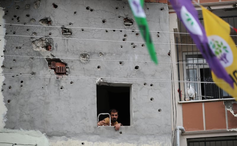 A man watches a campaign event by Turkey's main pro-Kurdish Peoples' Democratic Party (HDP) from a window of a building which was damaged during the security operations and clashes between Turkish security forces and Kurdish militants, in Silvan, a town in Diyarbakir province, Turkey, June 5, 2018. Picture taken June 5, 2018. REUTERS/Umit Bektas