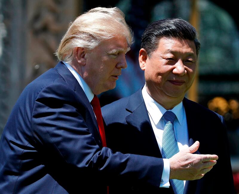 FILE - In this April 7, 2017, file photo, U.S. President Donald Trump gestures as he and Chinese President Xi Jinping walk after their meetings at Mar-a-Lago in Palm Beach, Fla. A year after Trump tried to disarm Xi at Mar-a-Lago with smooth talk and hospitality, he's resorted to hard ball and found that Xi is willing to throw it back. But at least for now, the acrimony over trade is unlikely to spill over into sensitive national security issues.(AP Photo/Alex Brandon, File)