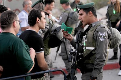 An Israeli soldier checks the ID of a Palestinian man as Muslim worshippers walk through Israel's Qalandia checkpoint between Ramallah and Jerusalem, in the occupied West Bank / AFP