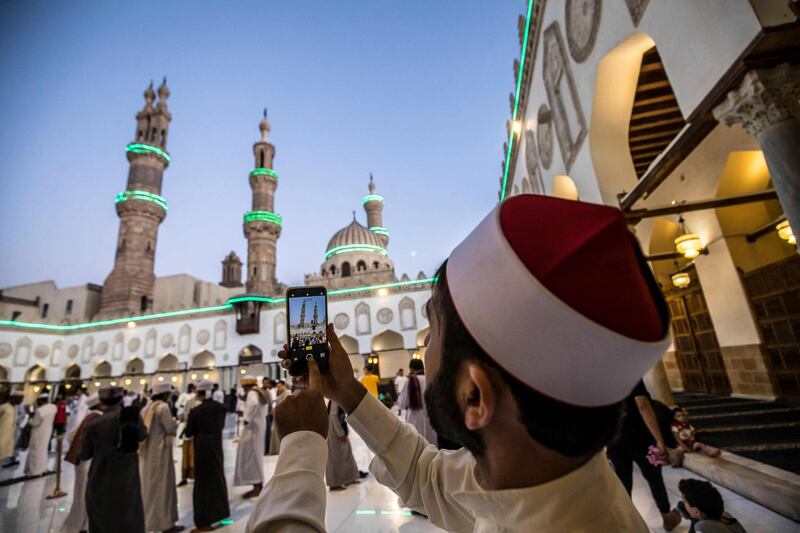 A Muslim worshipper from Afghanistan takes pictures during Eid Al Fitr prayers at Al Azhar mosque in Cairo. AFP