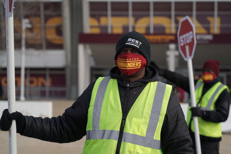A traffic guard wears a Washington Commanders face mask outside of Fedex Field. Willy Lowry / The National.