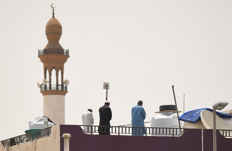 Workers pray on the roof of a residential building near a mosque in Dubai.  AFP