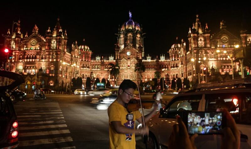 A Japanese musician is playing the violin for his personal music video in front of the illuminated Chhatrapati Shivaji Terminus railway station in Mumbai.  Divyakant Solanki / EPA