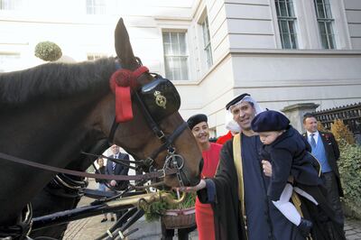 His Excellency Mansoor Abdulhoul following his visit with Her Majesty The Queen at Buckingham Pallace for the presentation of diplomatic credentials. Seen here with his wife in red with black hat, Victoria Devin and the deputy Marshal of the Diplomatic Core with feathers in hat. Outside the Lanesborough Hotel in central London where the reception HE Mansoor Abdulhoul's in D'honneur took place.