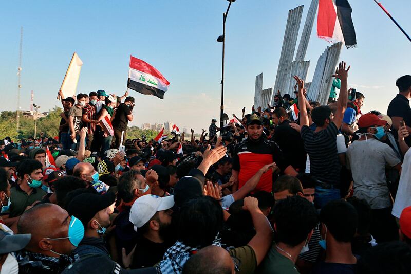 Anti-government protesters remove barriers on a bridge leading to the Green Zone during a demonstration in Baghdad, Iraq, Saturday, Oct. 26, 2019. Iraqi protesters converged on a central square in the capital Baghdad on Saturday as security forces erected blast walls to prevent them from reaching a heavily fortified government area after a day of violence that killed scores. (AP Photo/Khalid Mohammed)