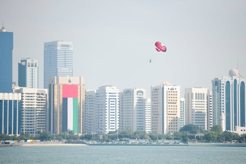 Parasailing with the UAE colours during the 51st National Day long weekend at Abu Dhabi Corniche. Khushnum Bhandari / The National
