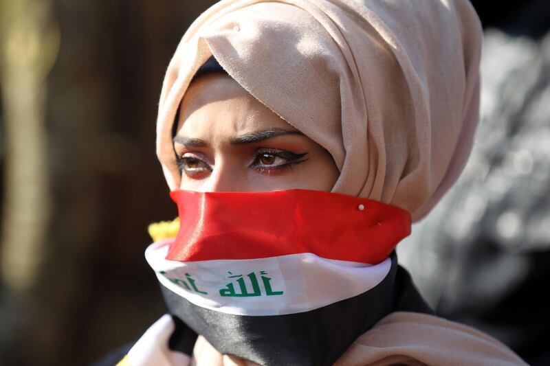 An Iraqi anti-government protester using the national flag as a mask takes part in a rally near the Ministry of Higher Education in the capital Baghdad on January 14, 2020. AFP