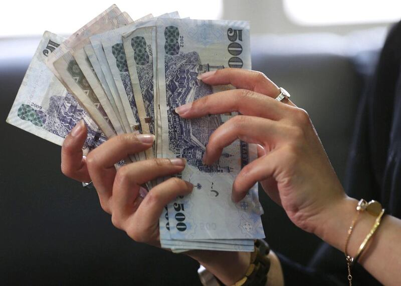 A Saudi woman shows Saudi riyal banknotes at a money exchange shop, in Riyadh. Faisal Al Nasser / Reuters