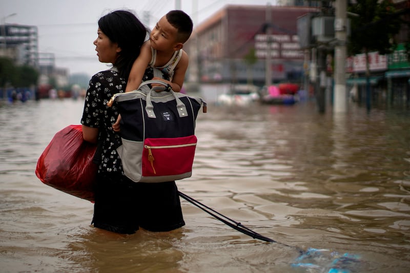 A woman carrying a child and belongings wades through floodwaters in Zhengzhou, in China's Henan province, on July 23, 2021. By Aly Song, Pulitzer Prize finalist for Feature Photography. Reuters