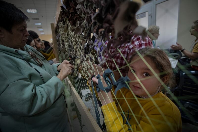 A Ukrainian girl helps to weave a camouflage net for the Ukrainian army, in Odesa. EPA