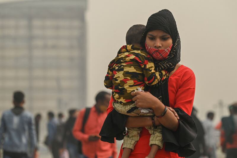 A woman carrying a child walks across a footbridge in heavy smog in New Delhi. AFP