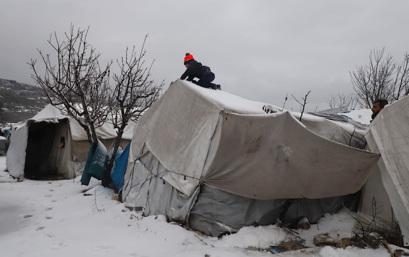 A young Syrian boy clears the snow covering a tent at a camp for internally displaced people, near the city of Jisr al-Shugur on the border with Turkey, in the Idlib governorate of northwestern Syria. AFP