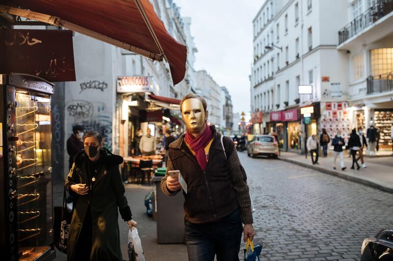 A man wears a golden mask costume walks down a street in Paris. Some doctors expressed relief but business owners despaired as France prepared to shut down again for a month to try to put the brakes on the fast-moving virus. The new measures are set to come into effect at midnight. AP Photo