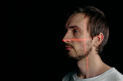 Profile on man in the dark with red lasers scanning his face