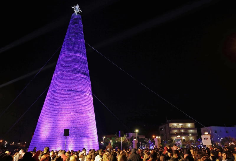 Lebanese visitors gather around a Christmas tree made of discarded plastic water bottles in the northern coastal town of Chekka, on December 15, 2019. AFP