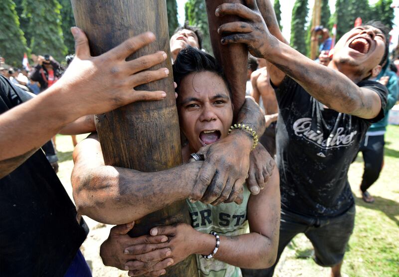 People take part in a competition to climb greased poles, on which prizes and flags are attached, to celebrate Indonesia's Independence Day in Denpasar, on the Indonesian resort island of Bali. Indonesia marks the 72nd anniversary of its independence from Dutch rule each year on August 17.  Sonny Tumbelaka / AFP.