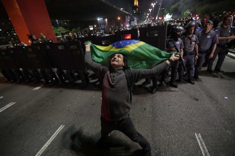 Supporters of Jair Bolsonaro celebrate their victory as members of the military police stand guard in Sao Paulo. EPA