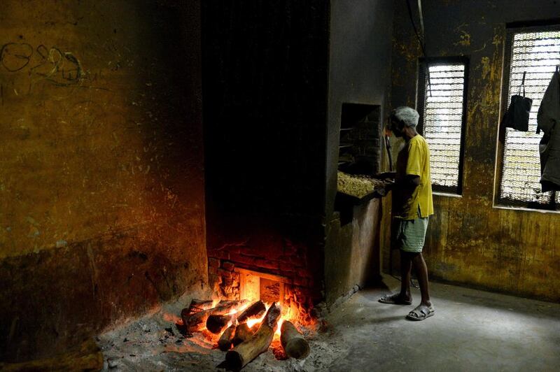 A factory worker puts a tray containing bundles of bidis, in a hot brick oven, to dry at The New Sarkar Bidi Factory in Kannauj.