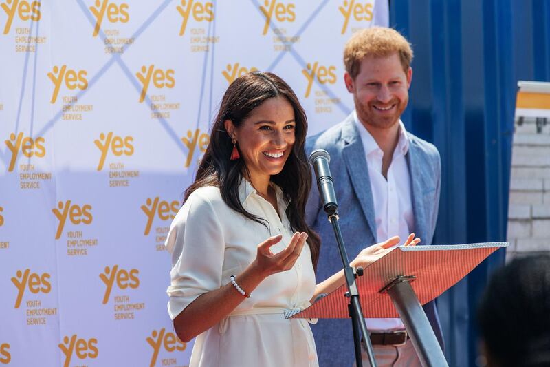 (FILES) In this file photo taken on October 2, 2019 Meghan, Duchess of Sussex (L), is watched by Britain's Prince Harry, Duke of Sussex (R) as she delivers a speech at the Youth Employment Services Hub in Tembisa township, Johannesburg.  Britain's Prince Harry and his wife Meghan handed out meals to sick people in Los Angeles, in their first known public activity since moving to California at the start of the state's coronavirus lockdown. The pair, who have formally stepped down as senior members of the British royal family, first volunteered with Project Angel Food last on April 12, 2020, delivering food to homes. / AFP / Michele Spatari

