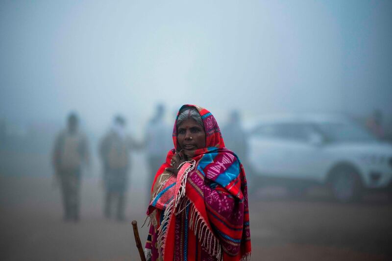 TOPSHOT - A woman walks along a street under heavy foggy conditions in New Delhi on December 30, 2019. / AFP / Jewel SAMAD
