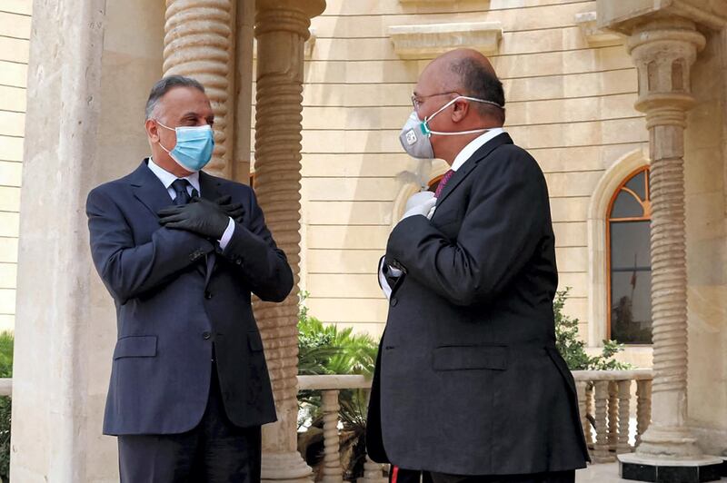 This handout photograph released by the Iraqi President's Office on May 28, 2020 shows President Barham Salih (R) receiving Prime Minister Mustafa Kadhimi at Salam Palace in the capital Baghdad, as they meet without shaking hands while both clad in masks due to the COVID-19 coronavirus pandemic. (Photo by - / Iraqi Presidency Media Office / AFP) / === RESTRICTED TO EDITORIAL USE - MANDATORY CREDIT "AFP PHOTO / HO / IRAQI PRESIDENT'S PRESS OFFICE" - NO MARKETING NO ADVERTISING CAMPAIGNS - DISTRIBUTED AS A SERVICE TO CLIENTS ===