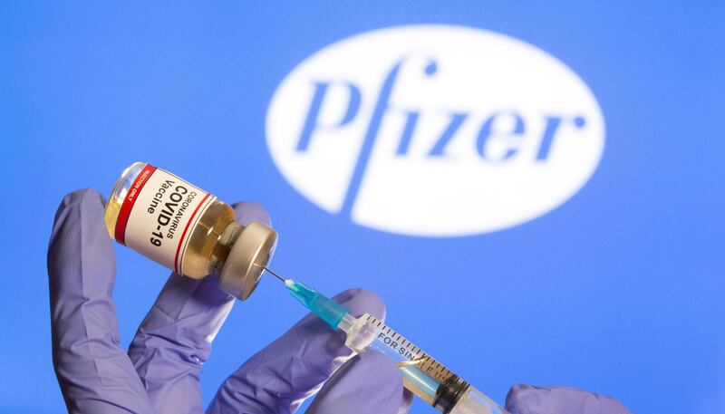 FILE PHOTO: FILE PHOTO: A woman holds a small bottle labeled with a "Coronavirus COVID-19 Vaccine" sticker and a medical syringe in front of displayed Pfizer logo in this illustration taken, October 30, 2020. REUTERS/Dado Ruvic/File Photo/File Photo/File Photo