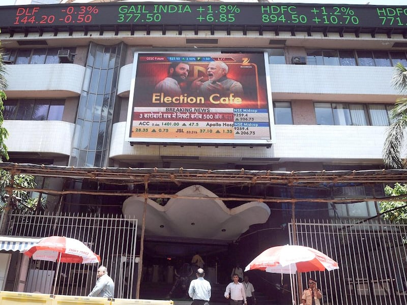Indian officegoers walk past the Bombay Stock Exchange (BSE) as the digital broadcast shows the 30-share benchmark index SENSEX cross 24,000 points during intra-day trade in Mumbai on May 13, 2014.  India’s stock market surged for the third straight day to a record high as exit polls indicated that Hindu nationalist party leader Narendra Modi was on course to become the country’s next prime minister.  INDRANIL MUKHERJEE / AFP