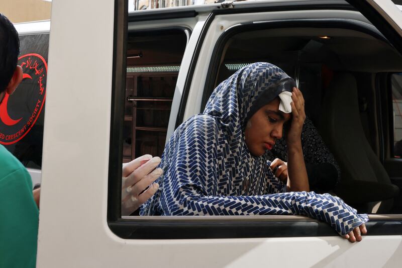 A woman leans against the window of an ambulance outside Kuwait Hospital after an Israeli strike in Rafah. AFP
