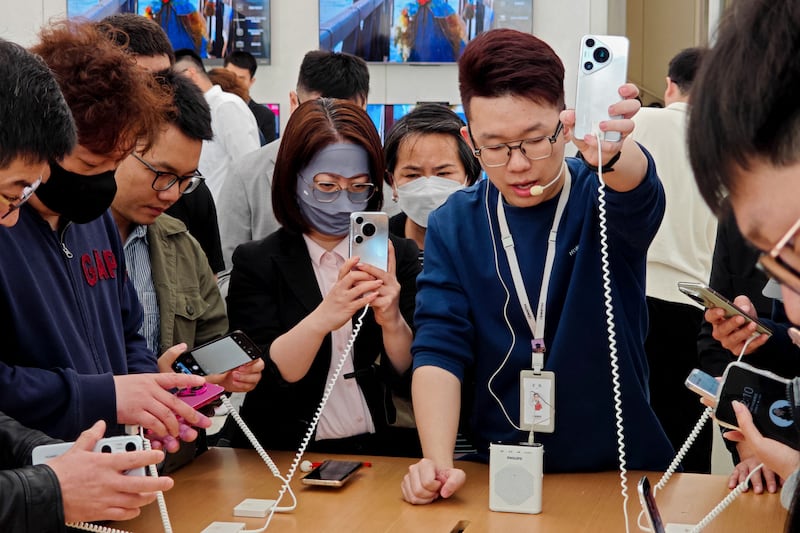People try Huawei's latest Pura 70 series phone at a shop in Shanghai. AFP