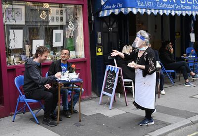 epa08526545 Customers sit in a tea room outside in Soho London, Britain, 04 July 2020. Pubs, restaurants, places of worship and other businesses reopen their doors across the UK on 04 July after more than three months of lockdown due to coronavirus pandemic.  EPA/FACUNDO ARRIZABALAGA