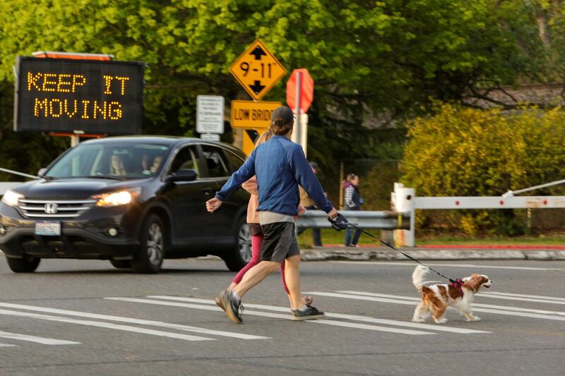 People walk their dog past a sign at Golden Gardens Park telling people to keep moving after Seattle Mayor Jenny Durkan reopened parks that were closed Easter weekend as efforts continue to help slow the spread of coronavirus disease in Seattle, Washington, US. Reuters