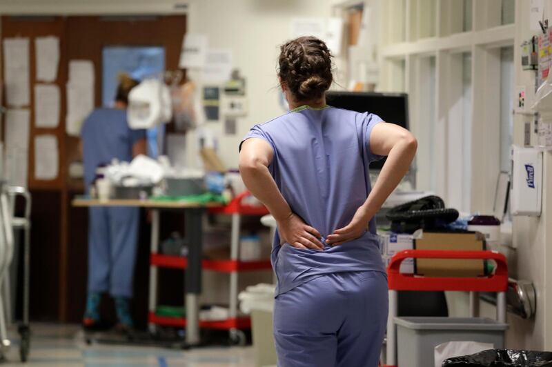 A nurse holds her back as she walks down a hallway in the Covid-19 Intensive Care Unit at Harborview Medical Centre. AP, File