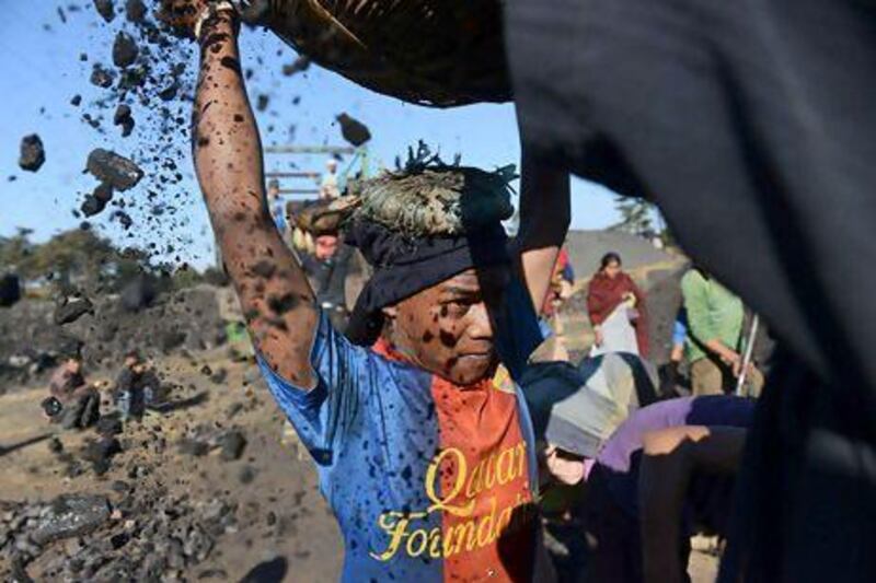 A teenage worker places a basket filled with coal on his head at a roadside coal depot in the Indian state of Meghalaya. Roberto Schmidt / AFP