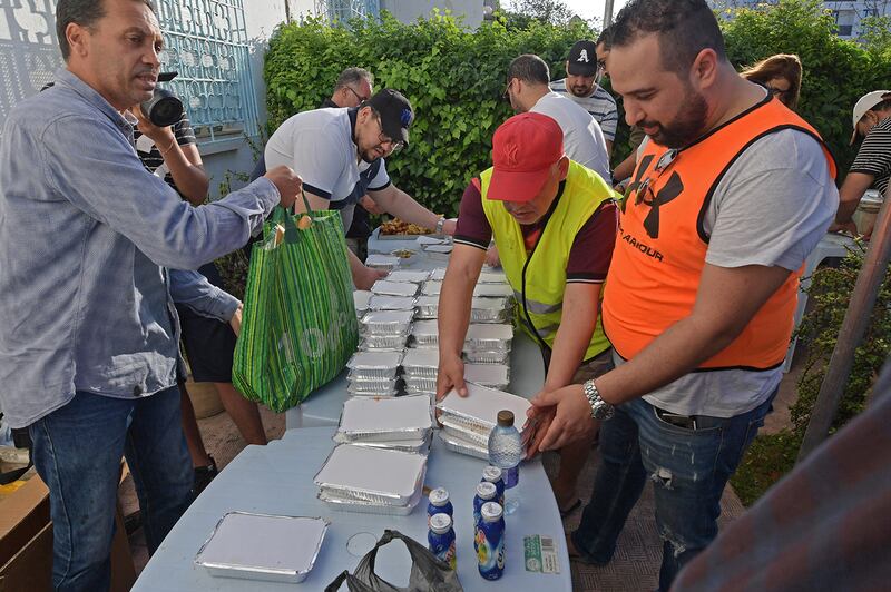 Tunisian volunteers distribute free Iftar meals on May 7, 2020 at the Ariana near Tunis during the Muslim holy fasting month of Ramadan. - Mosques in Algeria, Morocco and Tunisia have been closed to curb the spread of the novel coronavirus Covid-19, preventing special evening prayers. (Photo by FETHI BELAID / AFP)