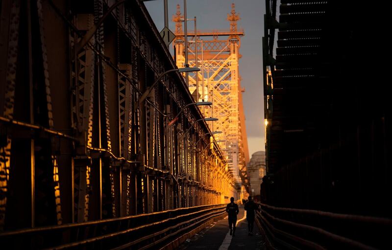 Two joggers run over the Queensboro Brigde towards Manhattan in the early morning hours in New York City.  AFP