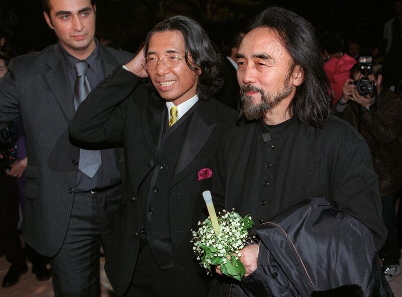 Fashion designer Kenzo, centre, smiles next to fellow Japanese designer Yohji Yamamoto, right, after showing his final collection on October 7, 1999. AFP