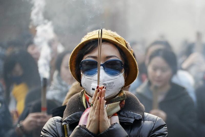 A Chinese woman wearing a mask and sunglasses to protect herself from smog, prays at the Yonghegong Lama Temple in Beijing. Andy Wong / AP Photo