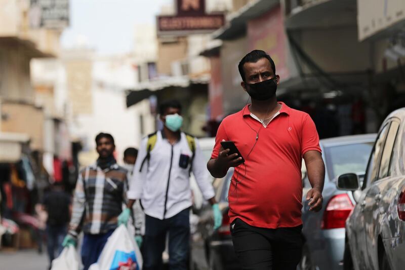 People wearing protective face masks walk in a street of Manama. EPA